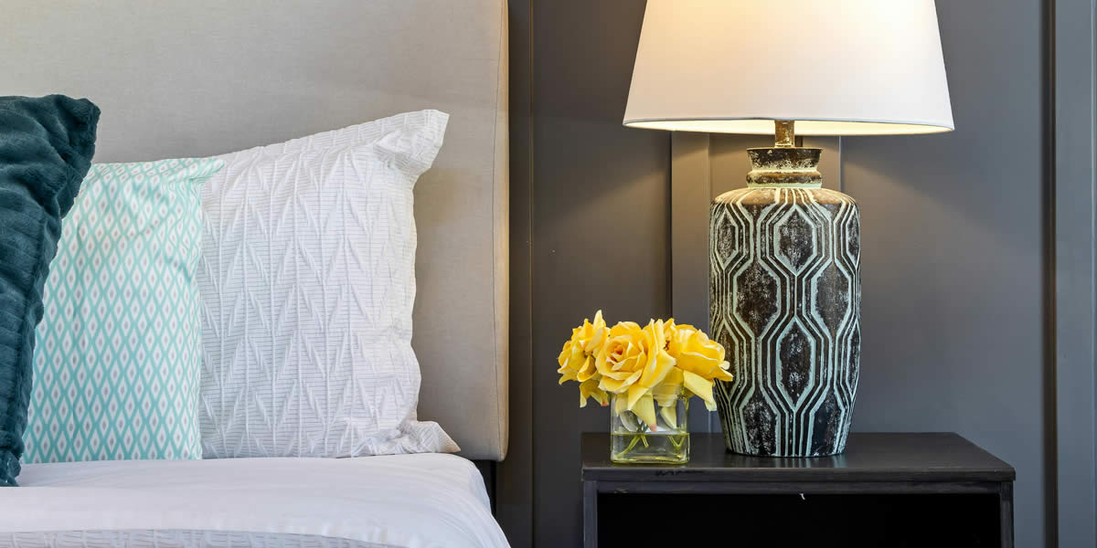A bedside table with a warm-toned lamp
